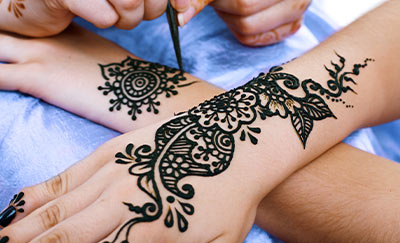 two hands with intricate black henna designs