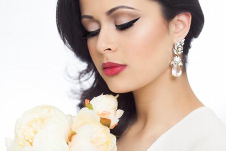 woman with elegant makeup holding white roses wearing pearl earrings